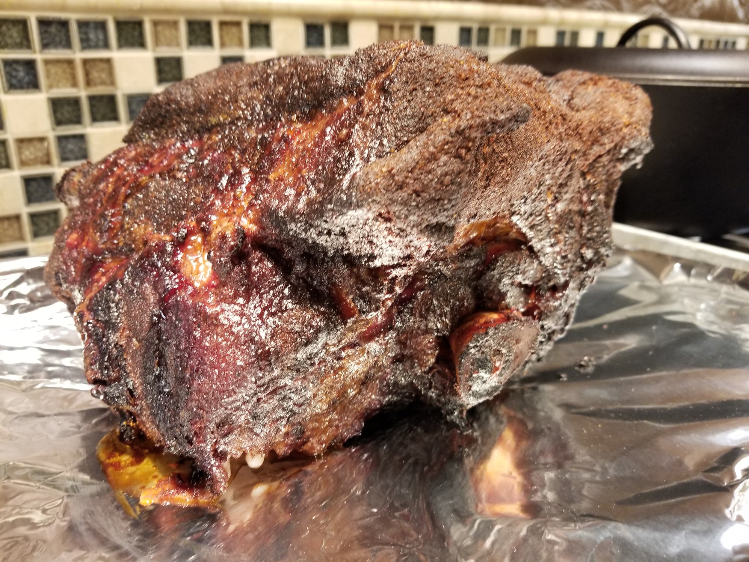 Smoked beef brisket with a dark, caramelized crust resting on aluminum foil, showcasing a juicy interior and rich texture, perfect for barbecue enthusiasts.